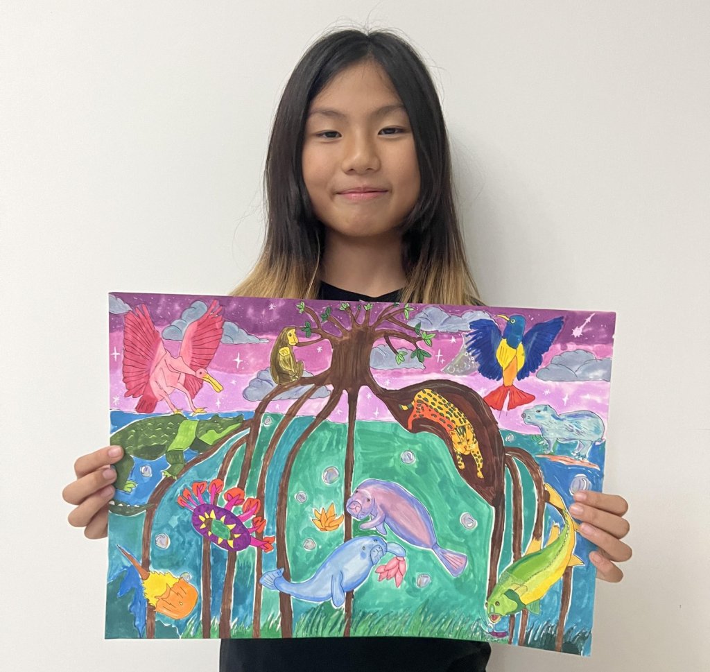 a student holds her mangrove-themed art